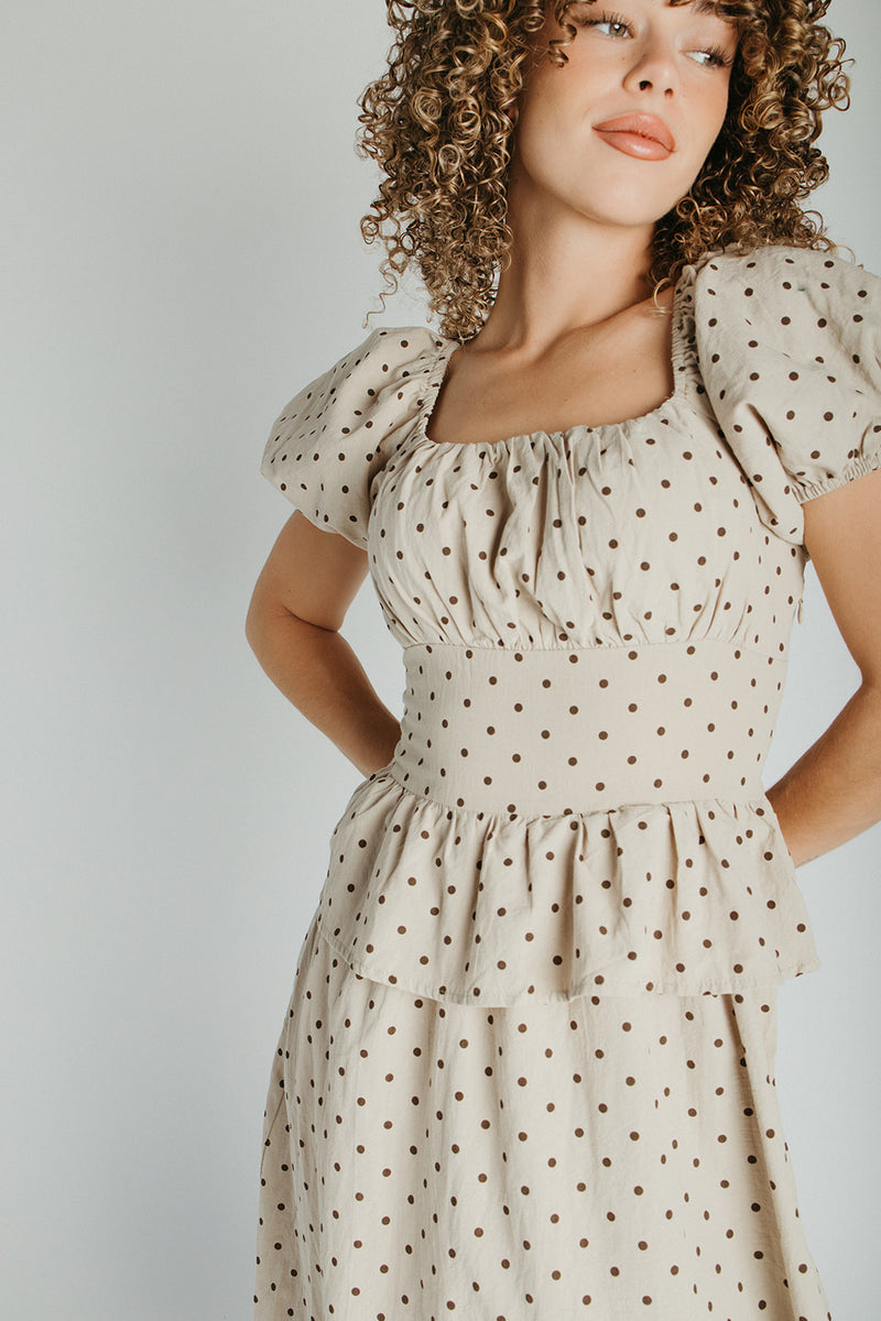 The Stacy Polka Dot Peplum Midi Dress in Taupe + Brown